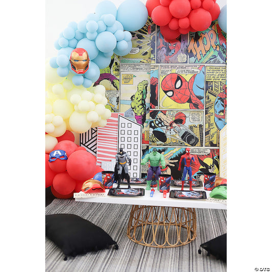 Marvel-themed party scene with comic-strip backdrop, balloon garland and superhero figures on a table